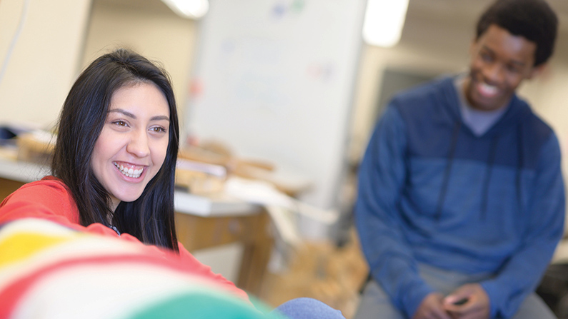 A student smiles while sitting in group with others