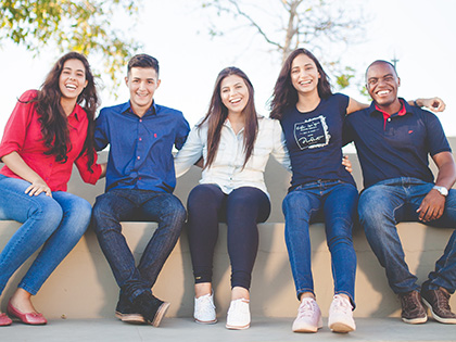 A group of five friends of different ethnic backgrounds sitting together outside