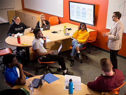 A teacher surrounded by students in the classroom.