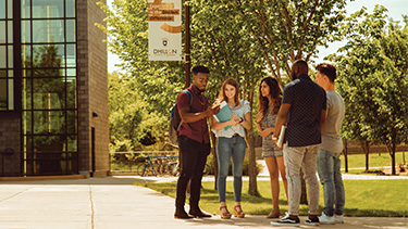 Five students standing outside the building and looking at the smart phone.